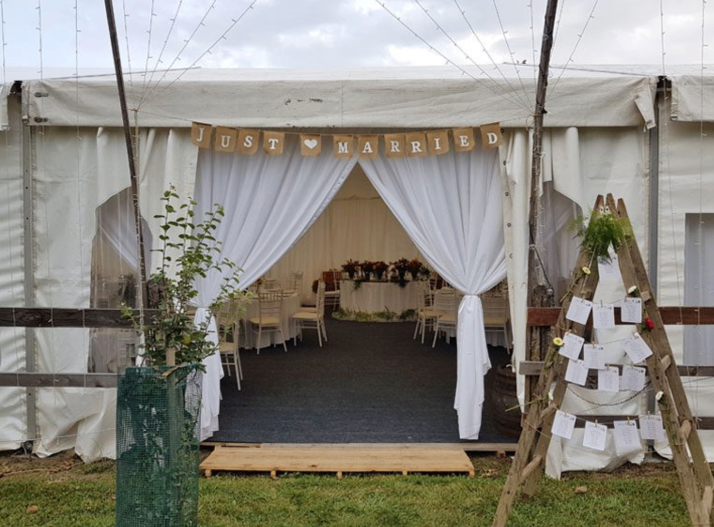 Wedding marquee entrance with white drapes and 'Just Married' banner