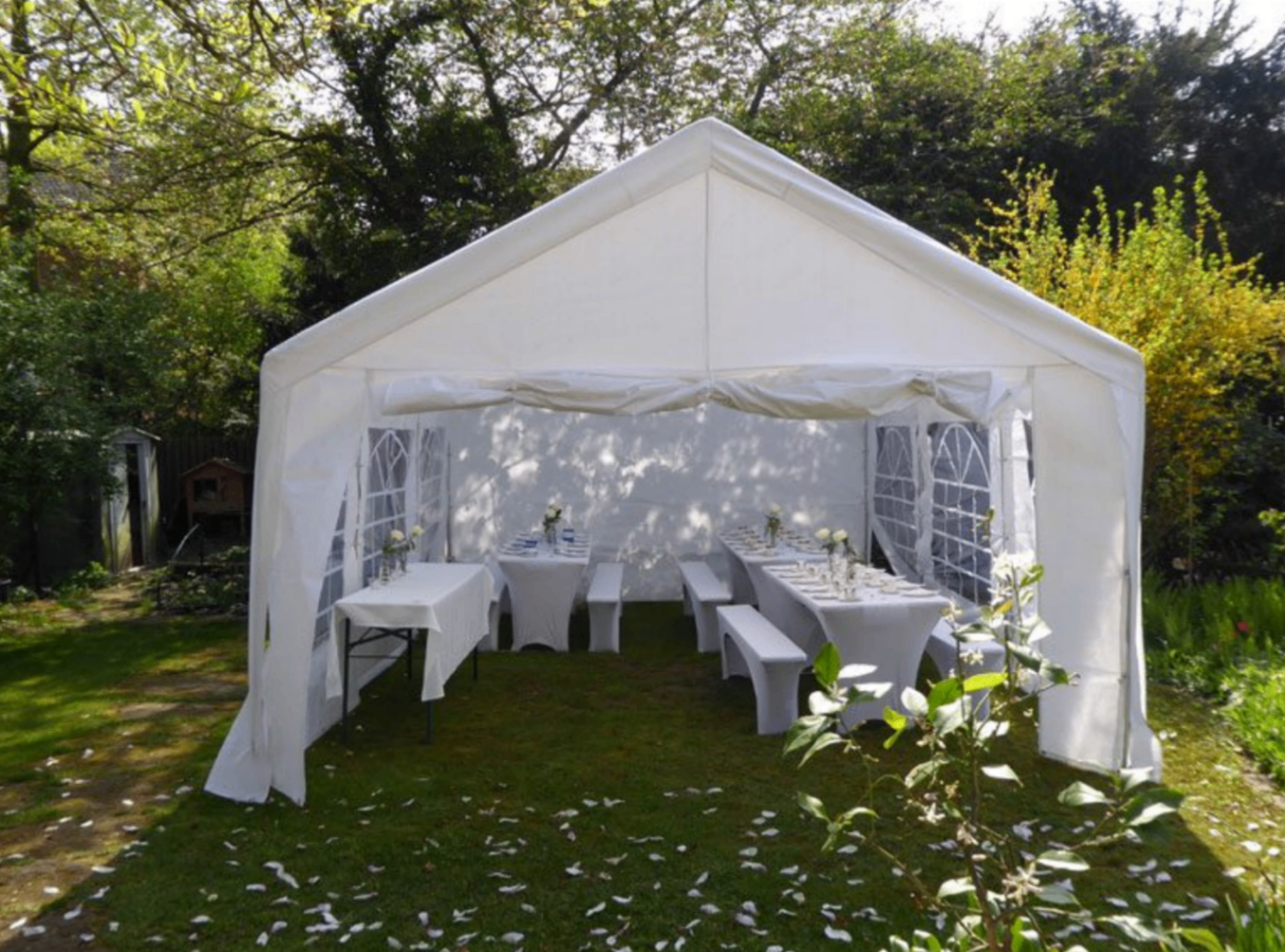White party tent in a spring garden with tables set for dinner